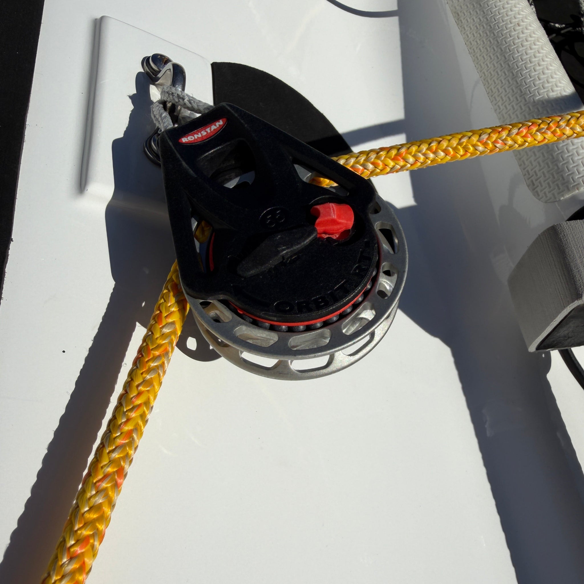 Yacht winch with yellow rope on a white surface
